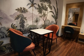 A room with a mural of tropical scenery, a wooden desk, two chairs, and a mirror.