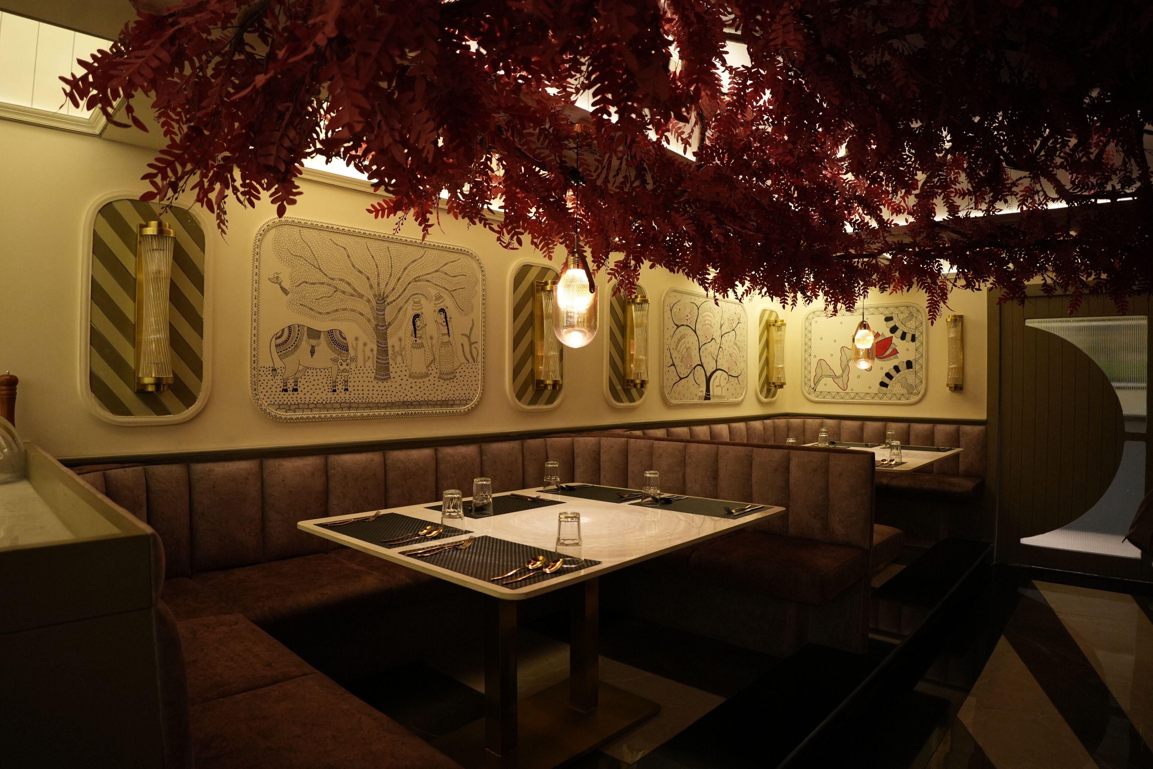 Un restaurante con cabinas y mesas, detalles decorativos en las paredes y lámparas colgantes.