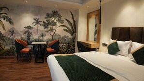 A hotel room with a bed, a desk, two chairs, a mirror, and a mural on the wall. - Trevon Twin Tree Inn (Dhanbad)