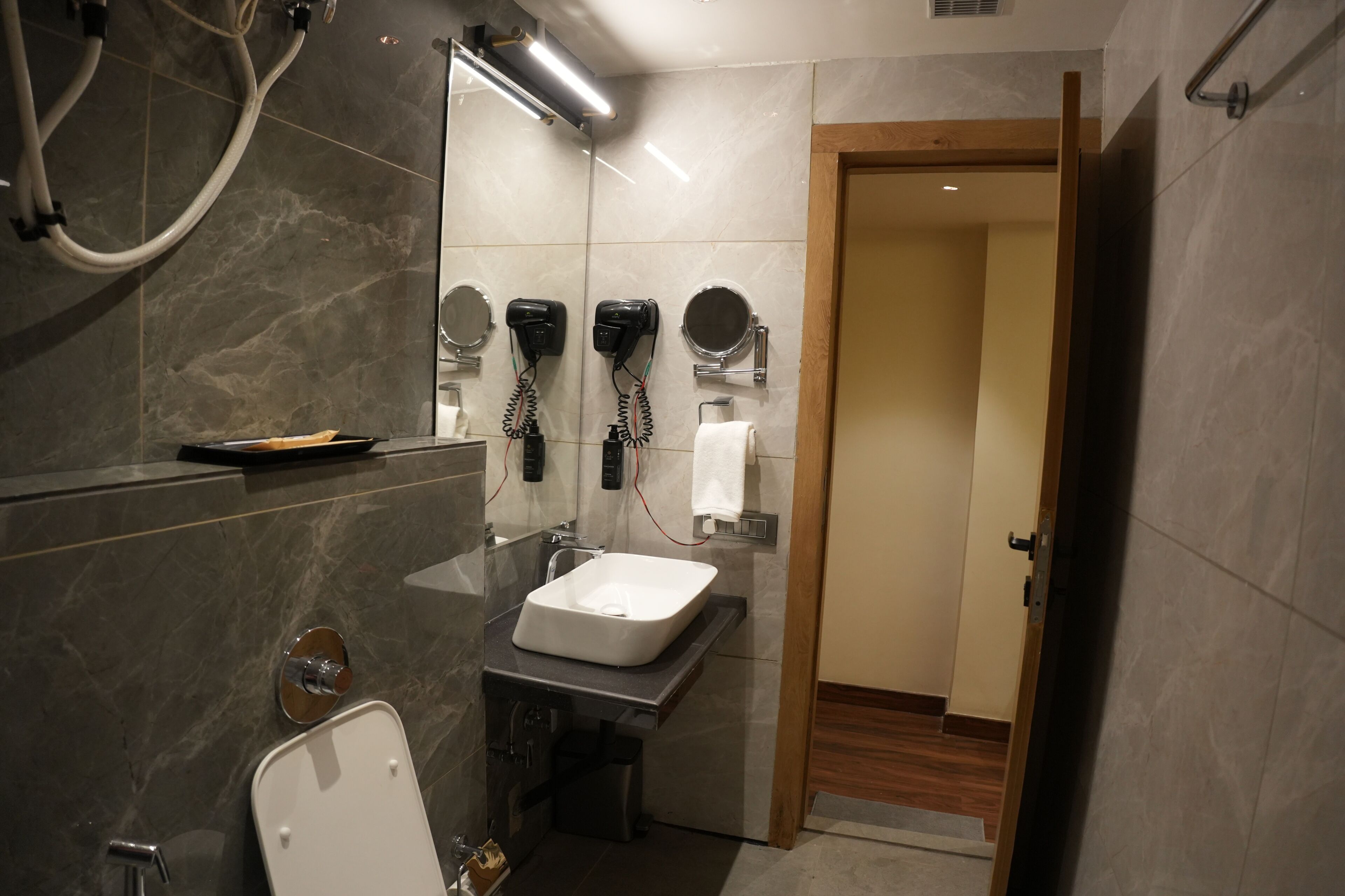 Ein modernes Badezimmer mit Waschbecken, Spiegel, Handtuchhalter und Föhn.