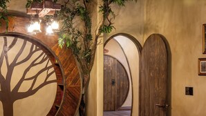 Quarto com silhueta de uma grande árvore na parede, portas de madeira e luminária pendente.
