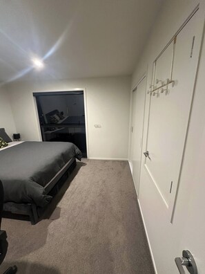 A bedroom with a bed, a wardrobe, a door with a handle, and a small window. - Affordable Room - Comes With Entire House (Upper Hutt)