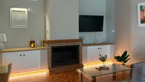 Una sala de estar moderna con chimenea, un televisor de pantalla plana, un ventilador de techo y un comedor.