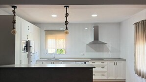 Una cocina moderna con una isla central, iluminación empotrada y vistas al comedor.