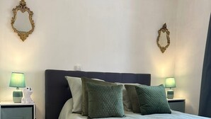 Une chambre à coucher bien rangée, avec un lit, deux tables de chevet, une commode et deux miroirs fixés au mur.