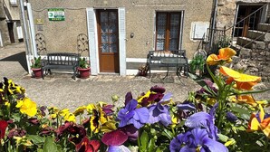 Un bâtiment doté d’une façade en pierre, de volets en bois et d’un banc à l’extérieur.