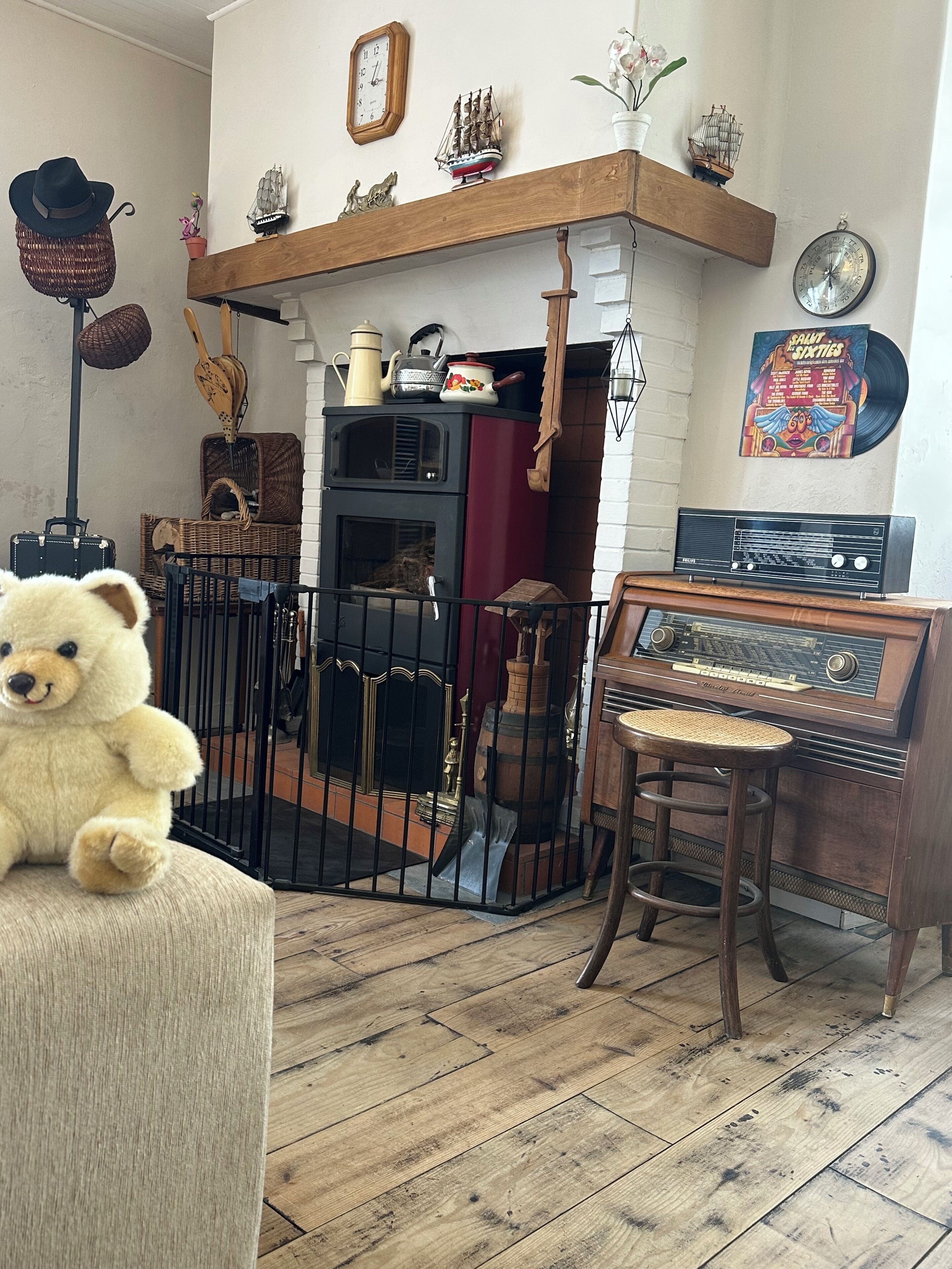 Una habitación de estilo antiguo con un cofre de madera, un oso de peluche, una radio y una chimenea.