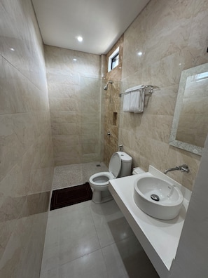 Un bagno moderno con cabina doccia in vetro, un water e un lavandino con specchio.