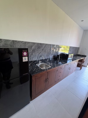 Una cucina moderna con frigorifero nero, lavello e pensili in legno.