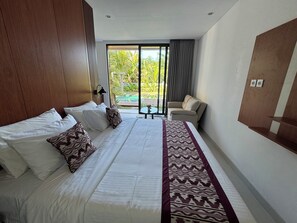 Una camera d'albergo con un letto grande, un divano, un tavolino e vista sul verde.