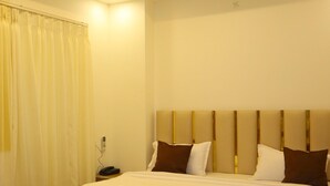 A modern hotel room with a large bed, a ceiling fan, recessed lighting, and a bedside table. - S S RESIDENCY (Gorakhpur)