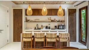 A kitchen with a central island, wooden cabinets, and hanging light fixtures. - Harmony Villa by DH (Gianyar)