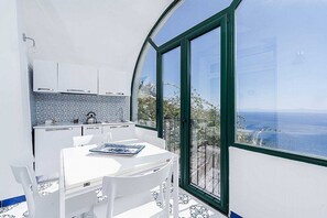 Eine moderne Küche mit weißen Schränken und Meerblick durch große Fenster.