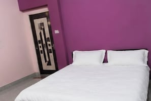 A room with a bed, a door, and a purple wall.