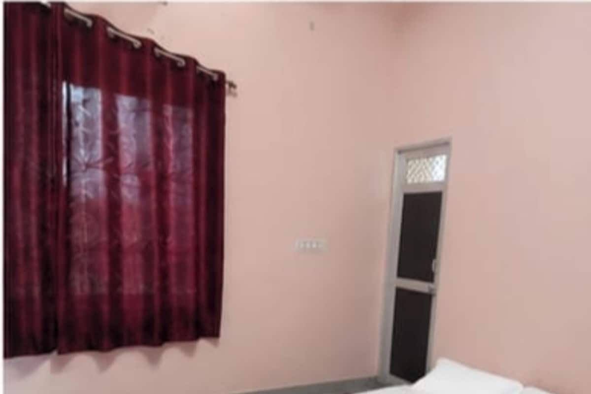 Un dormitorio con cama, ventana con cortinas y una puerta.