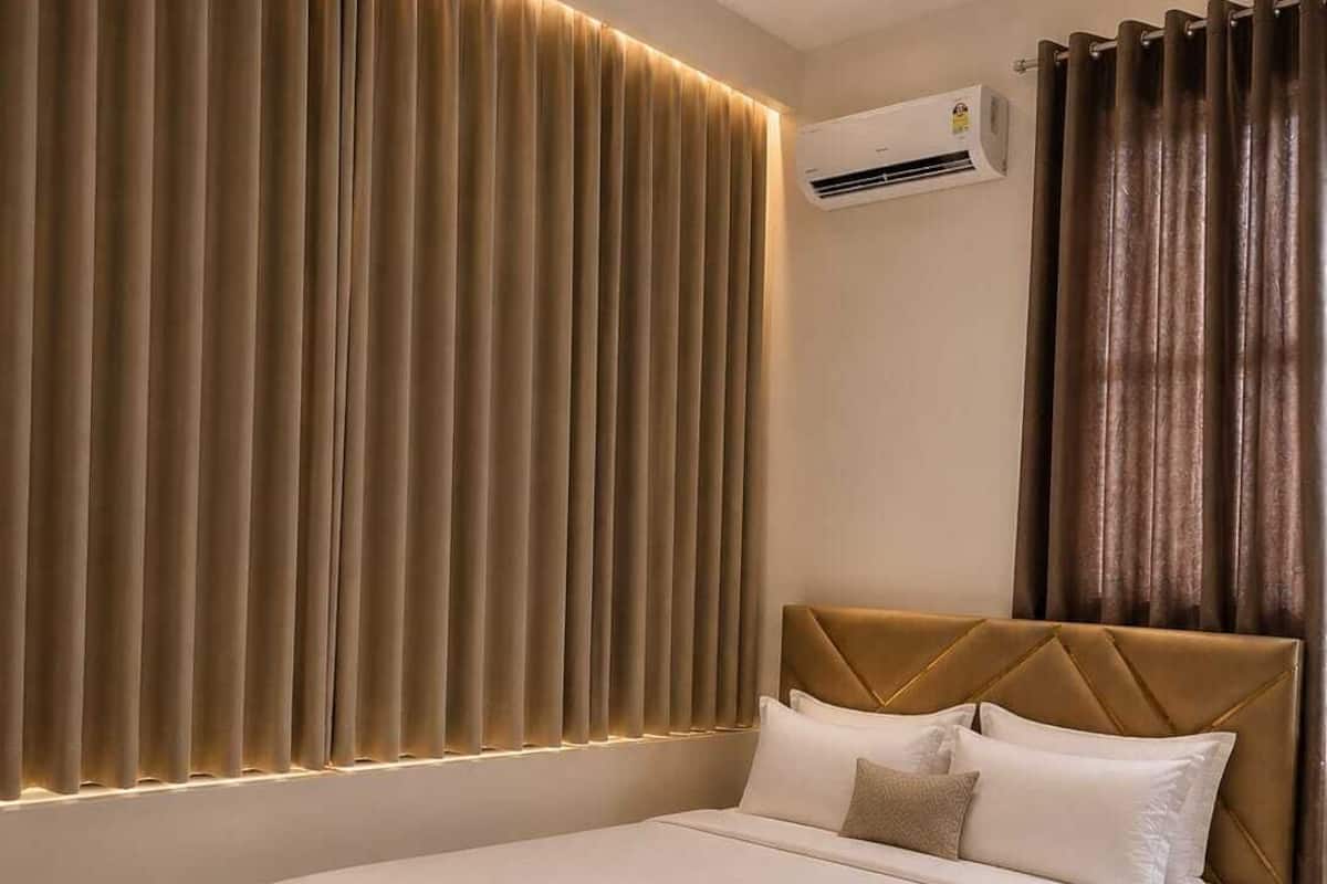 Un dormitorio moderno con cama, cortinas, un equipo de aire acondicionado y un ventilador de techo.