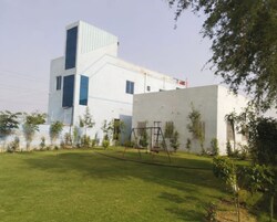 A modern building with a flat roof, a large window, and a swing set in the yard.