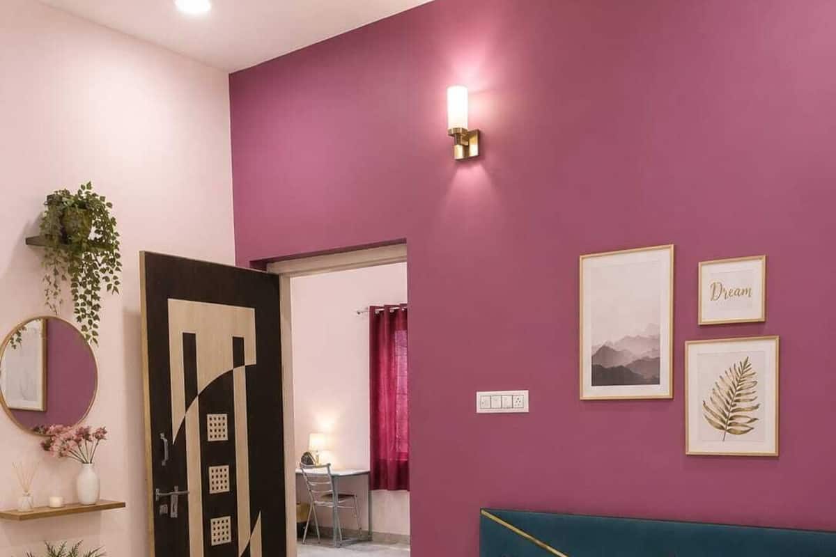 Un dormitorio con una cama, una puerta con diseño geométrico, una lámpara de pared y cuadros enmarcados.