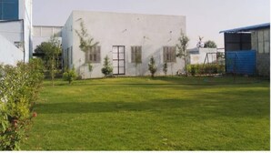 A building with a flat facade, a central door, and small trees in the yard. - Hotel Deluxe And Family Resturant (Lachhmangarh)