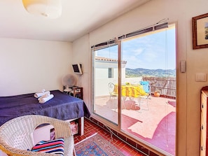 Une chambre avec un lit, une chaise, une table et un balcon offrant une vue.
