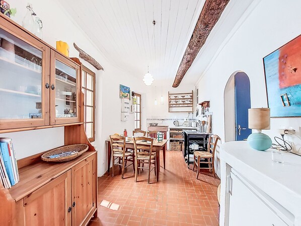 Une cuisine avec des meubles de rangement en bois, une table à manger avec des chaises et un réfrigérateur blanc.