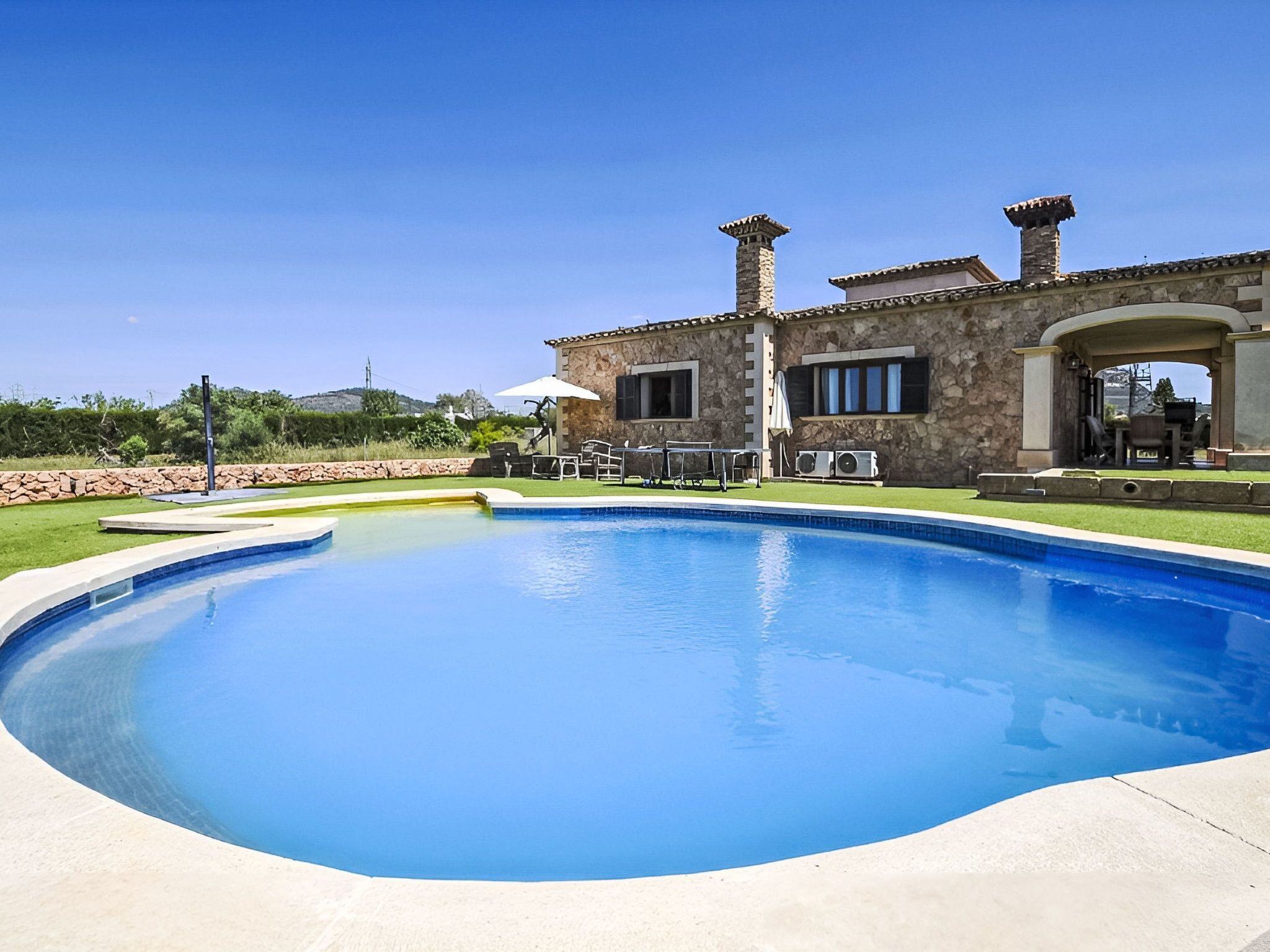 Ein Swimmingpool mit einem Haus aus Stein im Hintergrund.
