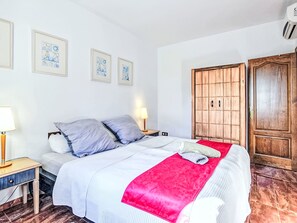 Ein Schlafzimmer mit Bett, Nachttischen, einem Kleiderschrank und gerahmten Bildern an der Wand.