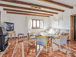 Ein Wohnzimmer mit Kamin, einer Sofagarnitur, einem Fernseher und einem Essbereich.