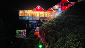 Un edificio de varios pisos con techo rojo y ventanas iluminadas de noche.