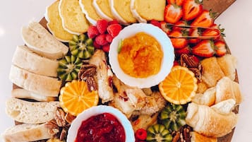 Una tabla de embutidos con quesos variados, frutas y pasteles.