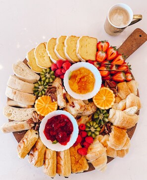 A charcuterie board with various cheeses, fruits, and pastries.
