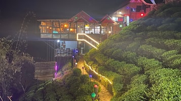 Un edificio de varios pisos con fachada de vidrio, una escalera visible y un área ajardinada.