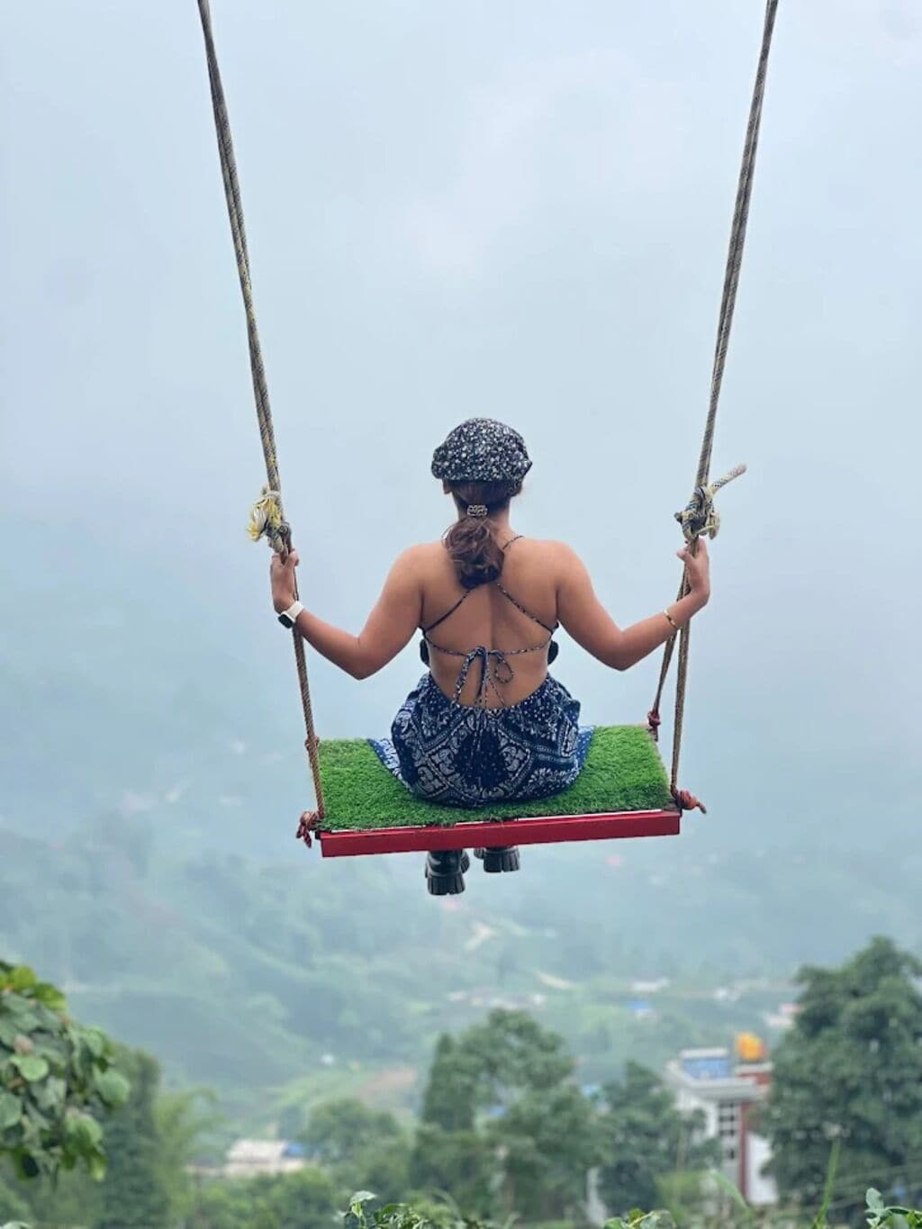 A person sitting on a swing suspended by ropes.