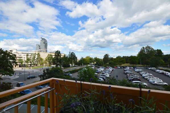 A parking lot with cars, a building with a modern design, and a clear sky. - Bright Studio in Center | Close to the Beach | Balcony (Gdynia)