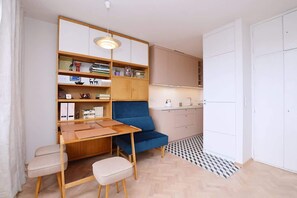 A compact living space with a kitchenette, a blue chair, a wooden desk, and a white wardrobe. - Bright Studio in Center | Close to the Beach | Balcony (Gdynia)