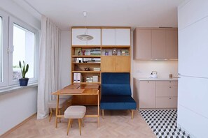 A compact room with a desk, chair, bookshelf, and kitchenette. - Bright Studio in Center | Close to the Beach | Balcony (Gdynia)