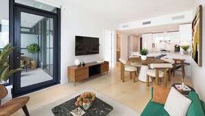Ein modernes Wohnzimmer mit Fernseher, Sofa, Couchtisch und Essbereich.