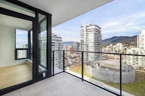 Een balkon met uitzicht op de stad, moderne gebouwen en een heldere lucht.