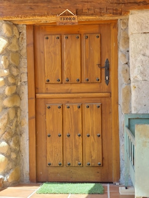 A wooden double door with metal studs and a metal handle, set in a stone wall.