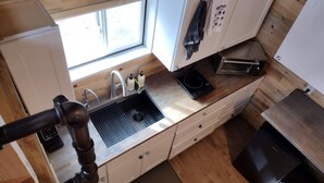 A compact kitchen with a sink, countertop, and a window.