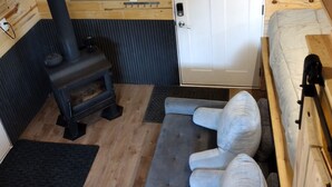 A compact room with a wooden interior, a small stove, a door with a towel, and a bench.