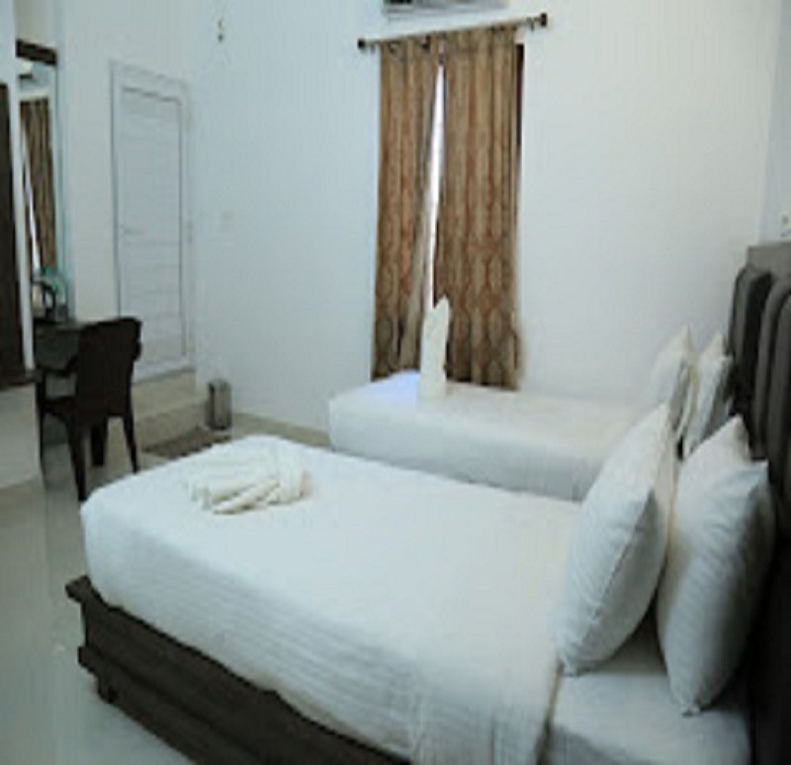 A bedroom with two beds, a desk, and a chair.