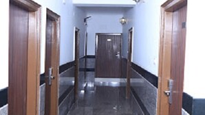 Un pasillo con puertas de madera, suelo de baldosas y una lámpara fijada a la pared.