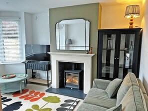 A living room with a fireplace, a sofa, a TV, and a cabinet. - 3 bedroom accommodation in Torquay (Torquay)