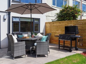 An outdoor patio with wicker furniture, a table, and a barbecue grill. - 3 bedroom accommodation in Torquay (Torquay)