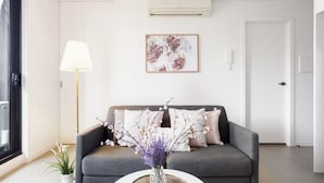 Ein modernes Wohnzimmer mit einer grauen Couch, einem runden Couchtisch und einer Vase mit Blumen.