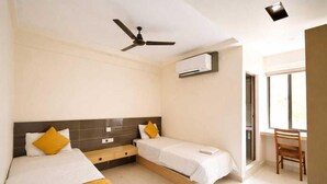 Ein Hotelzimmer mit zwei Betten, einem Deckenventilator, einer Klimaanlage und einem Fenster.