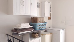 A laundry area with a washing machine, a drying rack, and a blue laundry basket on a shelf. - The Red house 1930 - frontside seaview apartment (Lido di Ostia)