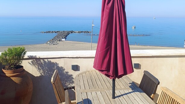 A wooden deck with a red umbrella, potted plants, and a view of the sea. - The Red house 1930 - frontside seaview apartment (Lido di Ostia)