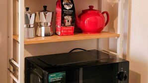 A kitchen with a microwave, coffee maker, and teapot on shelves, and a coffee bag. - The Red house 1930 - frontside seaview apartment (Lido di Ostia)